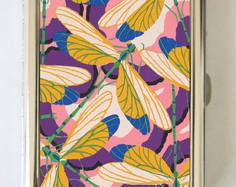 May include: A silver metal cigarette case with a colorful design of dragonflies with yellow, white, blue, green, and purple wings on a pink and purple background.
