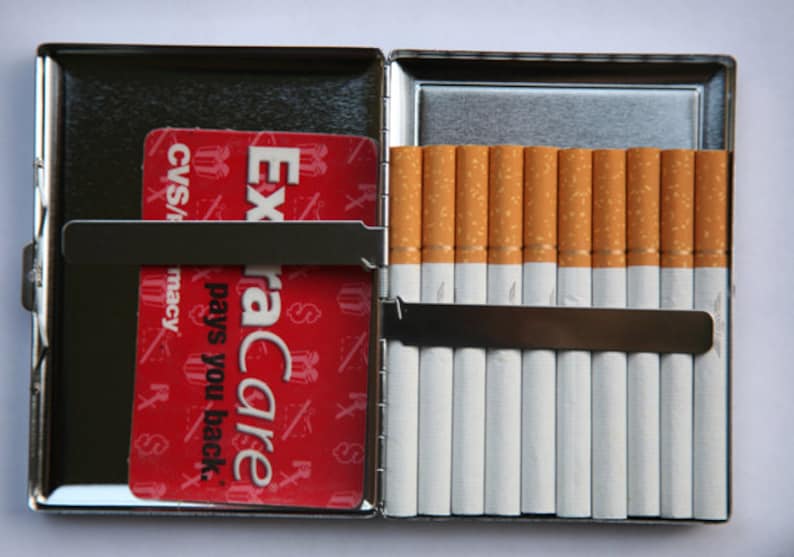 May include: A silver cigarette case with a red ExtraCare card inside and a row of cigarettes in the other side.