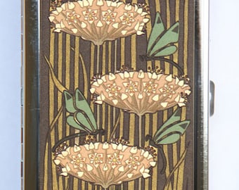 May include: A silver metal cigarette case with a floral design. The case features three pink flowers with green dragonfly accents on a brown and gold background.