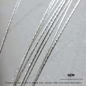 May include: Close-up of silver-colored, twisted wire. The wire has a textured surface and is arranged in parallel lines. The text "megabeadstore.com" is visible in the background.