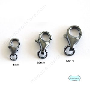 Könnte beinhalten: Drei silberfarbene Karabinerhaken in verschiedenen Größen: 8 mm, 10 mm und 12 mm. Die Karabinerhaken sind vor einem weißen Hintergrund abgebildet.