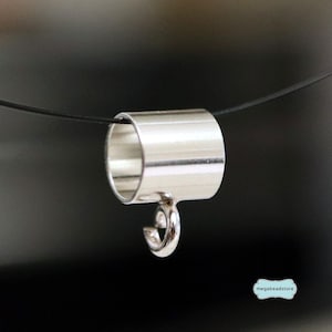 Peut inclure: Une bélière cylindrique de couleur argentée avec une finition lisse et polie. Le composant présente un design en tube creux avec une boucle attachée à la base, enfilé sur un cordon noir fin. Le texte megabeadstore est visible dans le coin.