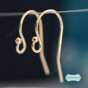 May include: A pair of gold-toned earring hooks with a small ball at the top of each hook.
