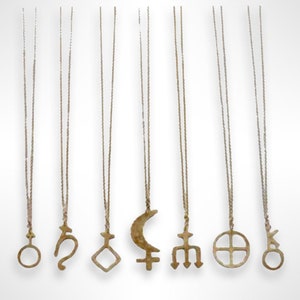 Samples of dainty, brass astrological glyph pendant necklace on gold plated chain. Glyphs of Saturn, dark Moon Lilith, Neptune, earth and Chiron.