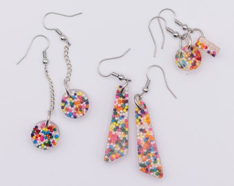 Triangular resin earrings with multicolored confetti and leaf shapes