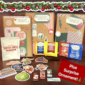 May include: Three wrapped brown paper packages with Christmas-themed decorations, including a red and green garland, a snowman sticker, and a red heart sticker. The packages are labeled with titles and authors of books, including "Steamy Christmas", "Christmas Romance", and "Winter Thriller".  The packages are surrounded by various Christmas-themed items, including a box of Swiss Miss hot chocolate, four boxes of Twinings tea, and a variety of stickers. The text "Plus Surprise Ornament!" is written in red on a white background.