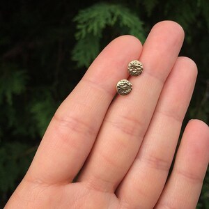 May include: A pair of gold hammered circle stud earrings.