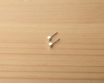 May include: A pair of silver cube stud earrings. The earrings are small and simple, and they would make a great gift for someone who likes minimalist jewelry.