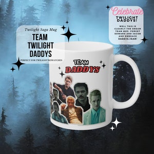 Op de afbeelding: Een witte keramische mok met een collage van afbeeldingen van de acteurs uit de Twilight-saga. De mok heeft de tekst "Team Twilight Daddys" en "Team Daddy's" in rood en zwart schrift. De tekst "Celebrate Twilight Daddys!" staat in een roze spraakballon met zwarte tekst. De tekst "Well this is clearly the dream team mug, forget Edward and Jacob and embrace Daddy's team!" staat in zwarte tekst.