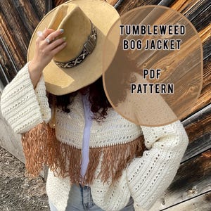 Pode incluir: Uma jaqueta de crochê branca com acabamento em franjas marrons. A jaqueta tem uma sobreposição de texto 'Tumbleweed Bog Jacket PDF Pattern'.