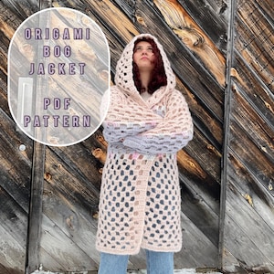 May include: A pink and white crochet jacket with a hood. The jacket is open at the front and has a loose fit. The text "ORIGAMI BOG JACKET PDF PATTERN" is written on a white oval in the top left corner of the image.