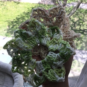 May include: Two crocheted doilies, one in green and white and the other in cream and pink, are stacked on top of each other.