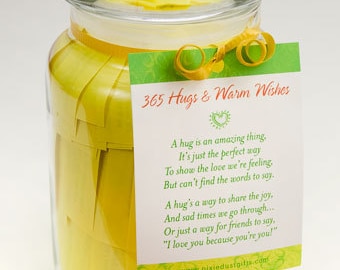 May include: A glass jar filled with yellow paper slips, each with a message. A tag attached to the jar reads "365 Hugs & Warm Wishes" and includes a poem about the power of hugs.