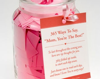 May include: A glass jar filled with pink paper slips, with a red and white tag attached that reads "365 Ways To Say, "Mom, You're The Best!" To last throughout the coming year, here are my thoughts for you. 365 folded up inside, to start each day anew. Just choose one to read each day, and know I Love You in every way! www.pixiedustgifts.com"