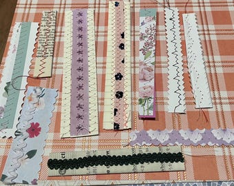 May include: A collection of decorative paper strips with various designs. Some strips feature floral patterns, while others have scalloped edges and stitched details. Colors include pink, purple, and green.
