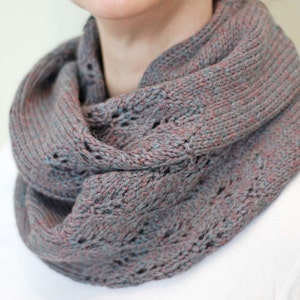 May include: A gray and pink knitted infinity scarf with a lacy pattern.