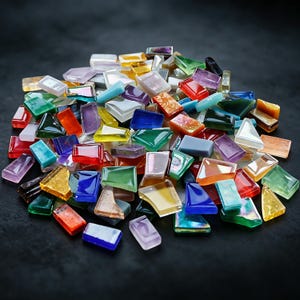 May include: A large collection of small, multi-colored glass tiles in various shapes including rectangles, trapezoids, and triangles. The tiles feature a mix of translucent, opaque, and iridescent finishes in shades of red, blue, green, yellow, purple, and white.