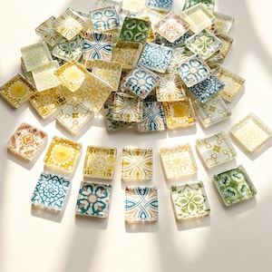 May include: A collection of square glass tiles featuring a variety of intricate patterns in shades of yellow, green, blue, and white. Each tile has a smooth, glossy finish and displays distinct geometric or floral motifs across its surface.