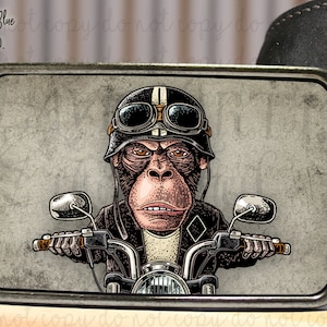 May include: A silver belt buckle with a vintage illustration of a chimpanzee wearing a helmet and goggles, riding a motorcycle.