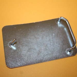 May include: A silver metal belt buckle with a smooth surface and a simple, curved metal loop.