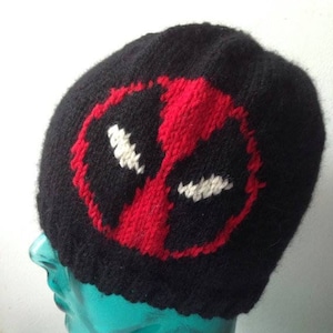 May include: Black knitted beanie with a red and white Deadpool mask design.