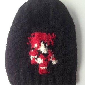 May include: Black knitted beanie with a red, white, and black pixelated design.