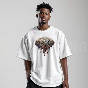 K&ouml;nnte beinhalten: Wei&szlig;es Kurzarm-T-Shirt mit einem Football-Motiv. Das Football-Design hat ein rissiges, strukturiertes Aussehen in Blau-, Orange- und Braunt&ouml;nen mit einem tropfenden Effekt. Das T-Shirt hat eine lockere Passform.