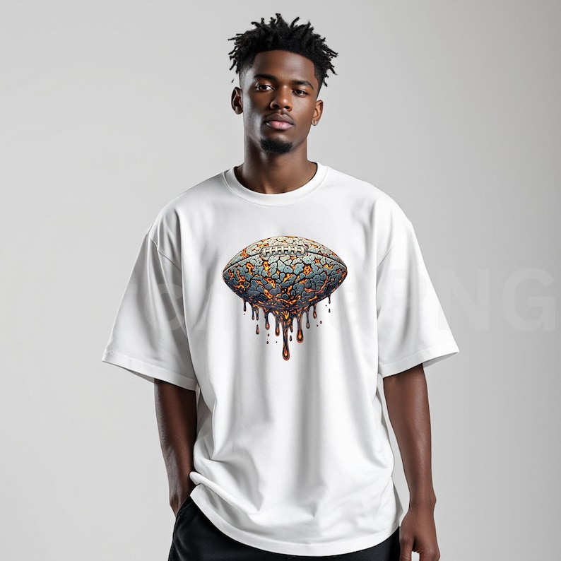 K&ouml;nnte beinhalten: Wei&szlig;es Kurzarm-T-Shirt mit einem Football-Motiv. Das Football-Design hat ein rissiges, strukturiertes Aussehen in Blau-, Orange- und Braunt&ouml;nen mit einem tropfenden Effekt. Das T-Shirt hat eine lockere Passform.