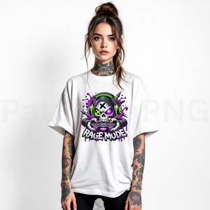 May include: White t-shirt featuring a skull wearing headphones and holding a game controller. The skull has a purple eye and a green X on the other eye. The words "RAGE MODE" are below the skull in a purple and white font.