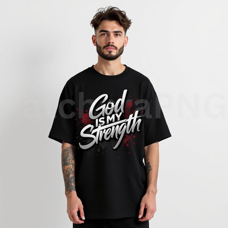 May include: Black t-shirt with the text "God is my Strength" in white and silver lettering. The text is over a red and black splatter design. The shirt has short sleeves and a crew neck.