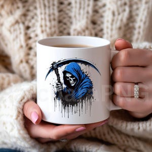 May include: White ceramic mug featuring a grim reaper design. The illustration depicts a skull in a blue hooded cloak holding a scythe, with black paint splatter details. The mug is held by a person.