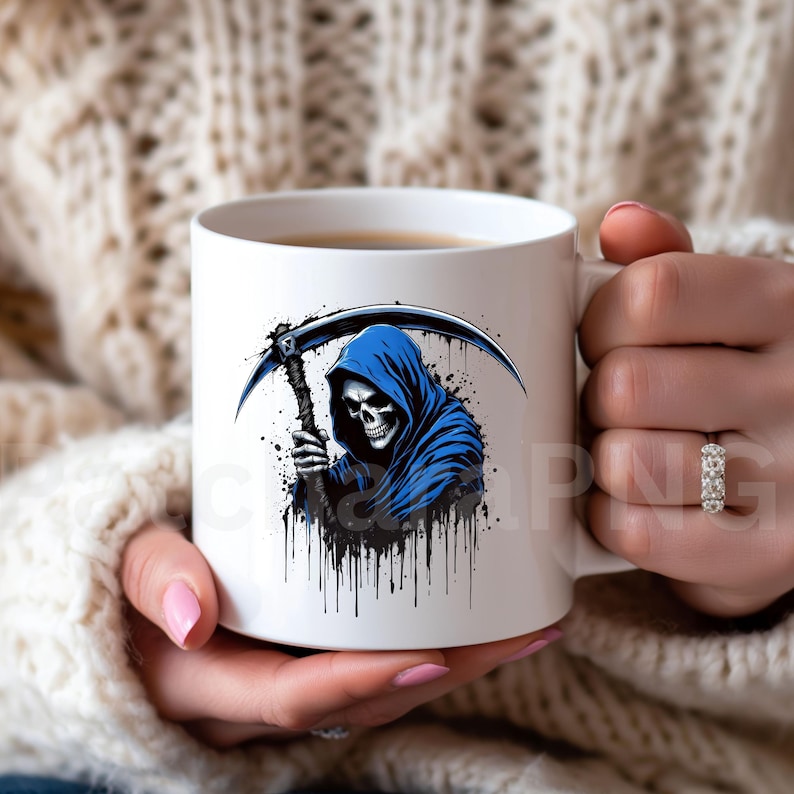 May include: White ceramic mug featuring a grim reaper design. The illustration depicts a skull in a blue hooded cloak holding a scythe, with black paint splatter details. The mug is held by a person.