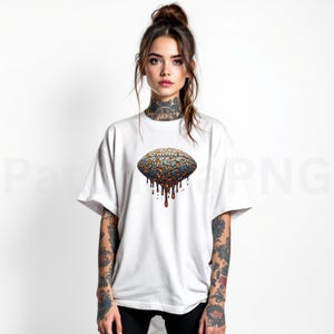 K&ouml;nnte beinhalten: Wei&szlig;es T-Shirt mit einem farbenfrohen, abstrakten Design einer ovalen Form mit rissiger Textur und tropfenden Elementen. Das Design enth&auml;lt Farbt&ouml;ne von Blau, Orange und Braun. Das Shirt hat kurze &Auml;rmel und eine lockere Passform.