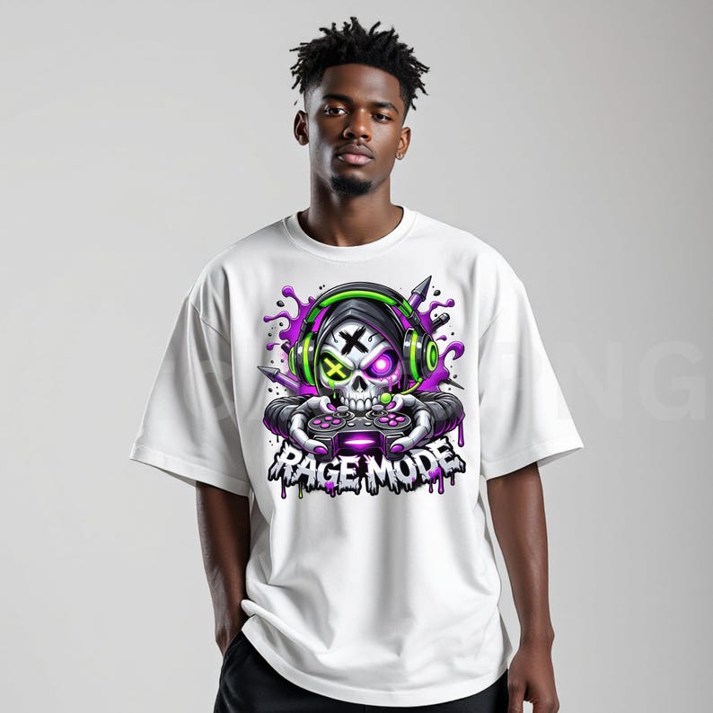 May include: White t-shirt featuring a skull graphic with headphones and a controller. The skull has purple and green accents, with the text "RAGE MODE" below. The design includes purple paint splatters.