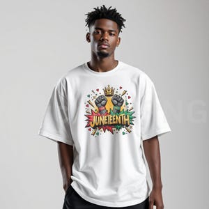 May include: White t-shirt featuring a colorful graphic design with the word "Juneteenth", two raised fists, and a crown. The design includes red, green, yellow, and black colors. The shirt is a casual, oversized fit.