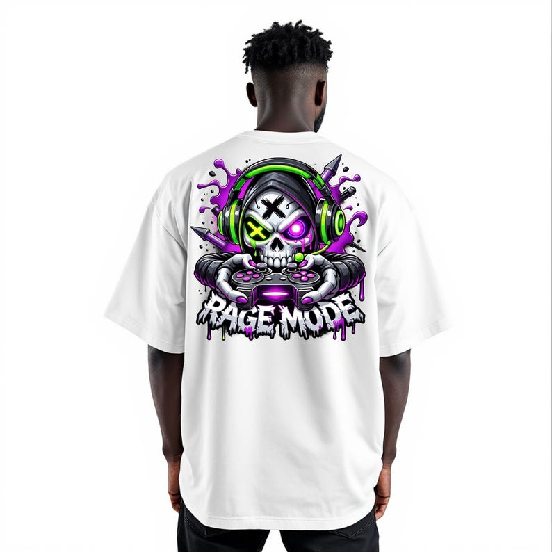 May include: White t-shirt featuring a skull graphic wearing headphones and holding a game controller. The design includes purple and green accents, with the words "Rage Mode" in a dripping font.