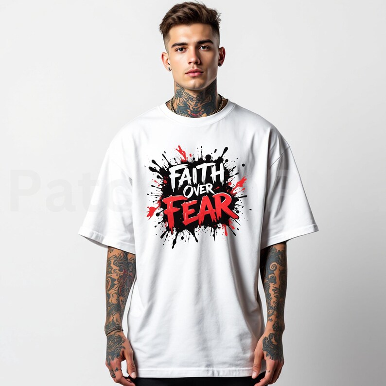 May include: White t-shirt with the words "Faith Over Fear" in a black, red, and white graphic design. The design has a splatter effect. The shirt has short sleeves and a crew neck.