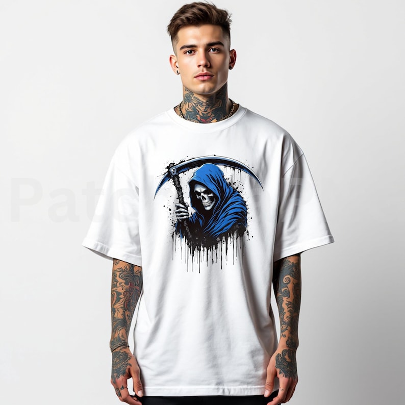 May include: White t-shirt featuring a graphic of the Grim Reaper in a blue hooded cloak, holding a scythe. The design includes black splatter effects. The shirt is a casual, short-sleeved style.