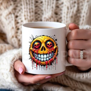 May include: White ceramic mug featuring a yellow, skull-faced emoji with red eyes and dripping blood. The design includes a wide, toothy grin and black splatter details, creating a spooky, Halloween-themed aesthetic. The mug is held by a person.