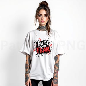 May include: White t-shirt with the words "Faith Over Fear" in red and black, surrounded by a splash design. The shirt has short sleeves and a crew neck.
