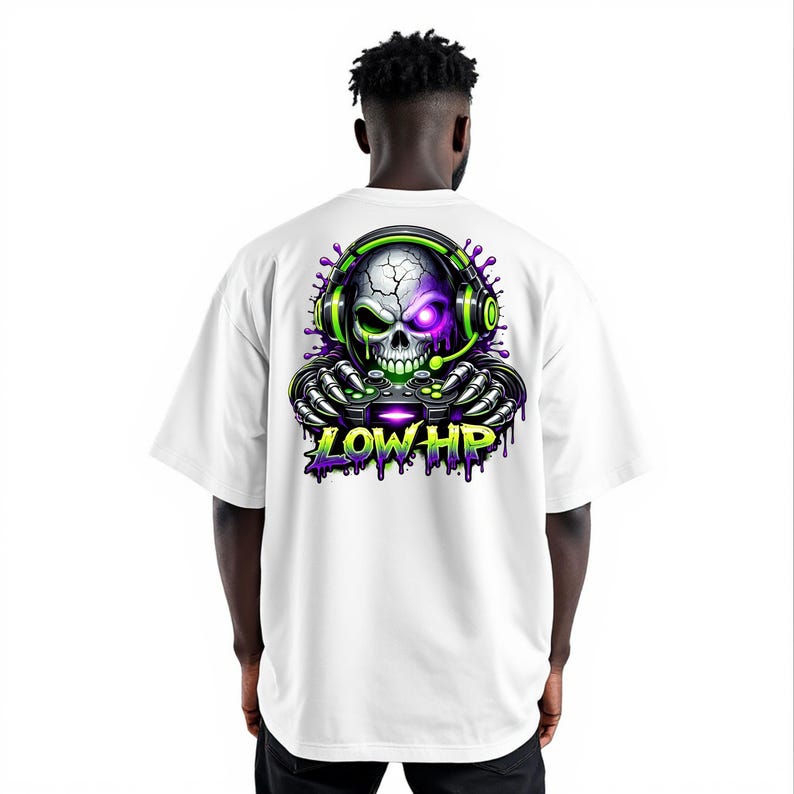 May include: White t-shirt featuring a vibrant graphic of a skull wearing a headset and holding a game controller. The skull has a purple eye and green accents, with the text "LOW HP" in green and purple. The design is centered on the back of the shirt.