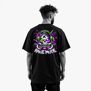 May include: Black t-shirt featuring a skull graphic wearing headphones and holding a game controller. The skull has a cross for an eye and a purple eye. The graphic includes the text "RAGE MODE" in white and purple.