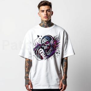 Peut inclure: T-shirt blanc avec un graphisme vibrant d'un cr&acirc;ne portant un casque et tenant une manette de jeu. Le cr&acirc;ne a des yeux roses et est entour&eacute; d'effets d'&eacute;claboussures violets et noirs, cr&eacute;ant un design dynamique.
