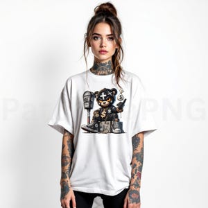 May include: White t-shirt featuring a detailed graphic of a black bear wearing a leather jacket, gold chain, and sneakers. The bear is holding a money bag and a cigarette, with a parking meter in the background.