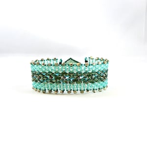 May include: A turquoise and silver beaded bracelet with a geometric pattern.