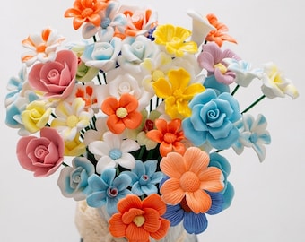 Könnte beinhalten: Ein Strauß aus bunten Keramikblumen in verschiedenen Blautönen, Rosa, Gelb, Orange und Weiß. Die Blumen sind in einer Vase arrangiert und sind eine schöne und einzigartige Dekoration für jedes Zuhause.