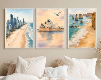 May include: A set of three framed wall art prints featuring watercolor illustrations of Australian landmarks. The left print shows a city skyline by the beach, the center print depicts the Sydney Opera House, and the right print shows coastal rock formations.