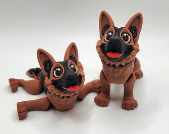 May include: Two brown and black German Shepherd dog figurines. One is standing and the other is lying down. Both have big eyes and a happy expression.