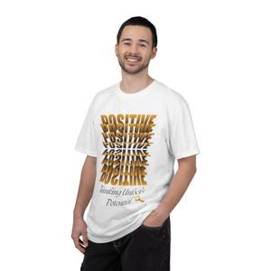 Può includere: T-shirt bianca con la parola "POSITIVE" impilata verticalmente in un carattere sfumato oro. Sotto la parola "POSITIVE" c'è il testo "Thinking Unlocks Potential" in un carattere più piccolo.