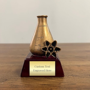May include: Gold-colored science award trophy with a beaker and atom design. The base is burgundy with a gold plaque that says "Custom Text Engraved Here".